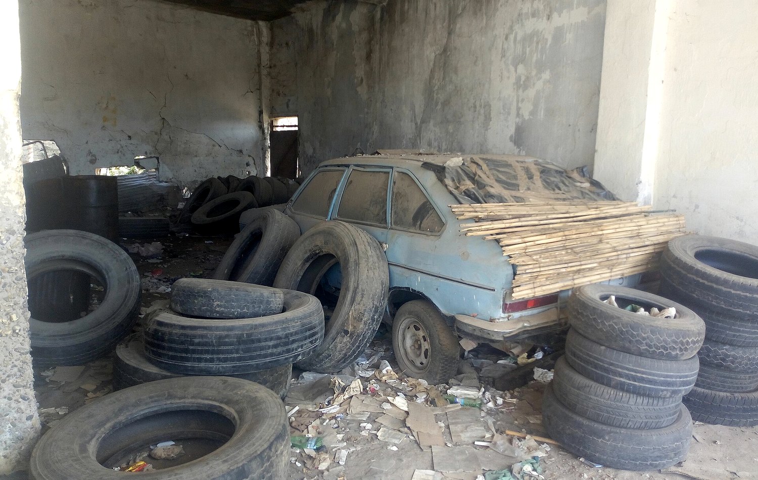 Used car inspected in a local garage with tires nearby