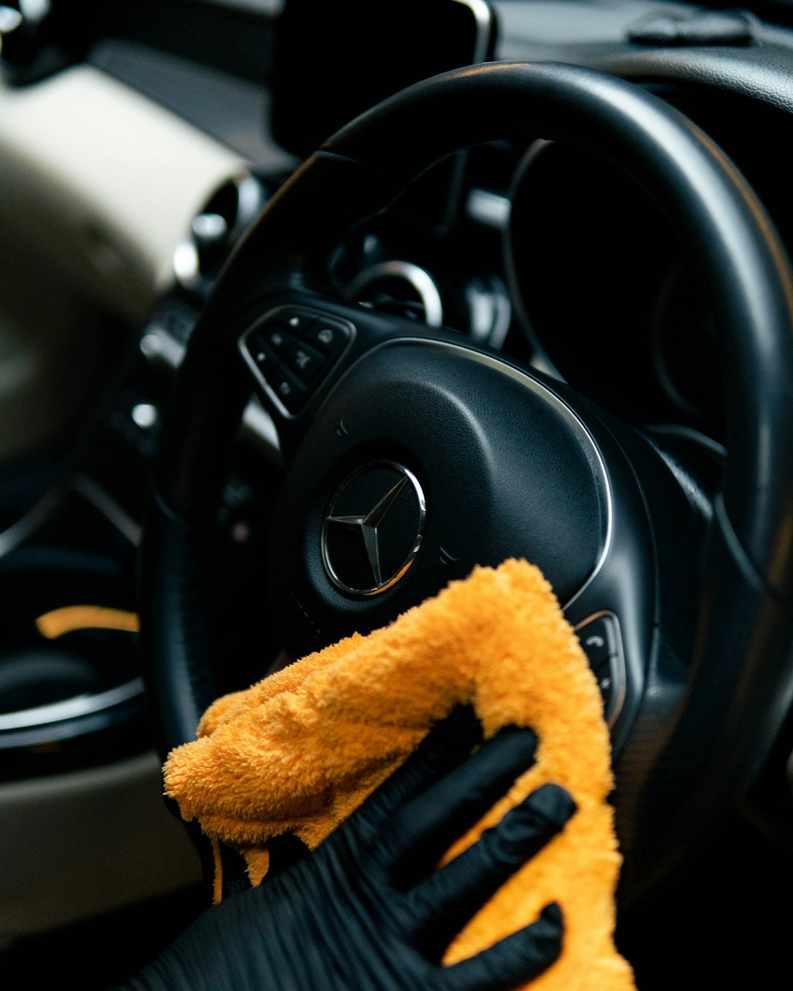 Yellow microfiber cloth cleaning a black steering wheel